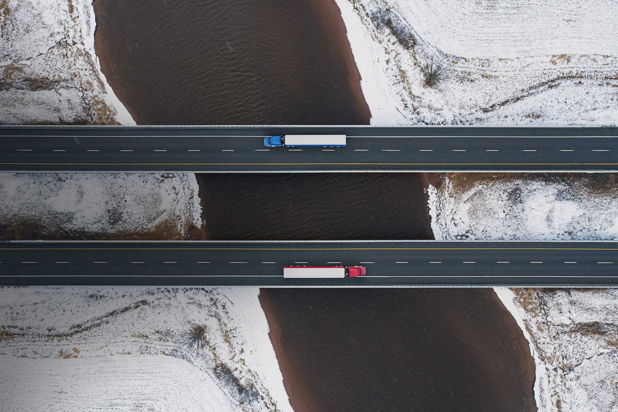 Aerial drone view of semi trucks crossing a tidal river
