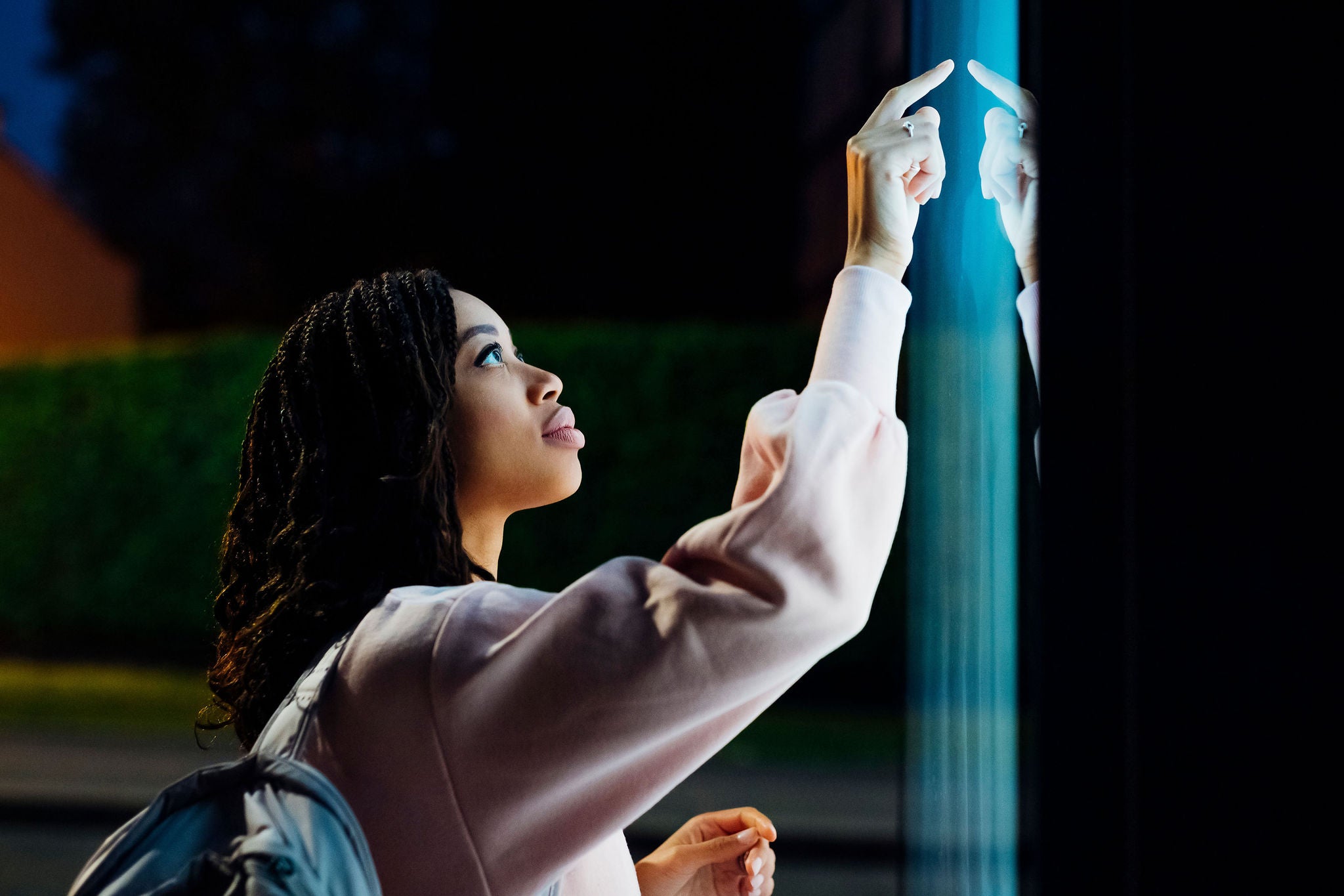Young woman touching kiosk screen at night